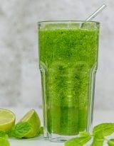 Groene komkommer smoothie met appel en limoen met blaadjes munt